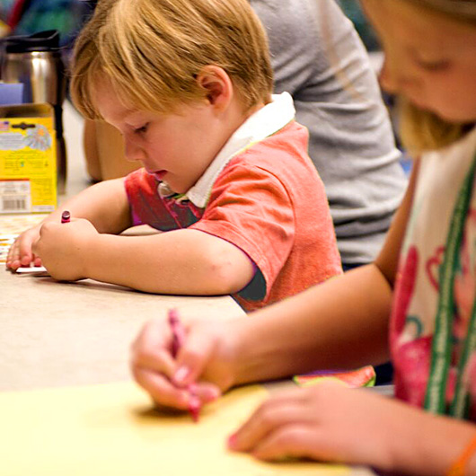 Mehrere Kinder arbeiten konzentriert an einem Tisch mit Stift und Papier