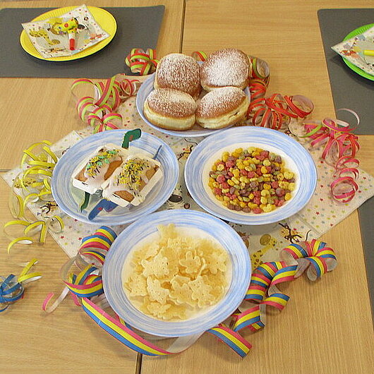 gedeckter Tisch mit Krapfen und Luftschlangen
