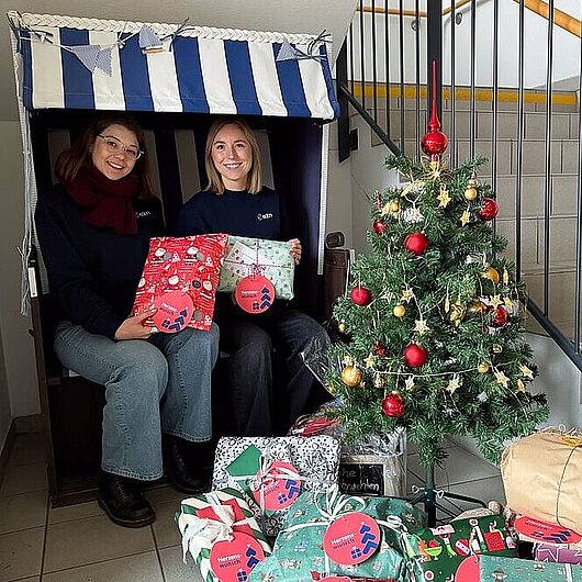 Zwei Damen in einem Strandkorb vor einem Christbaum