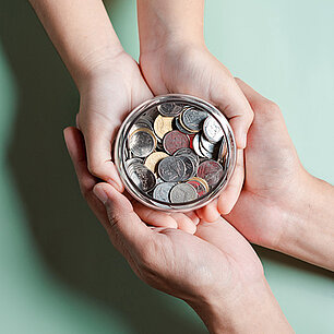 Auf Handfläche liegende Schale mit Münzen (Foto: Kiattisak/stock.adobe.com)