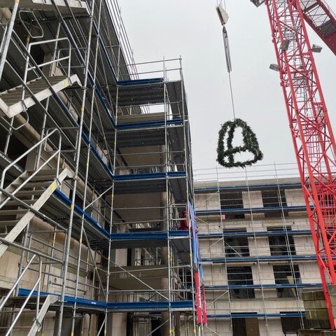 Kranz für das Richtfest wird mit dem Kran auf das Dach gehoben.