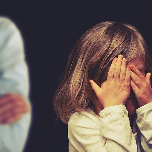 Ein Kind hält schützend seine Hände vors Gesicht.