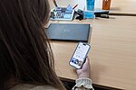Eine Frau hält ein Handy, auf dessen Bildschirm die App des Modellprojekts JMD digital-hub