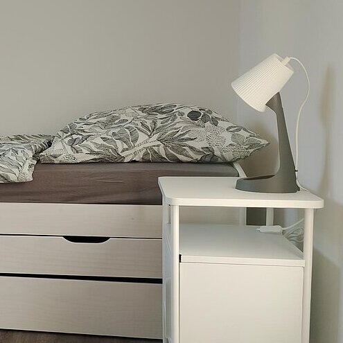 Bett und Nachttischlampe aus einem Zimmer des Jugendwohnen Korallenriff in Fürth