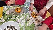 Fleißige Kinderhände, die aufgeschnittene Orangen mit Nelken spicken