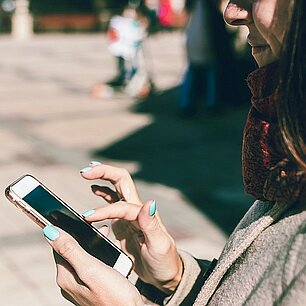 Eine junge Frau gibt Text auf ihrem Handy ein.