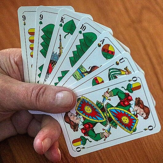 Eine Hand hält sieben Schafkopfkarten