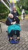 Ein gut gelaunter Mann im Rollstuhl und eine Frau bei einer Gartenparty