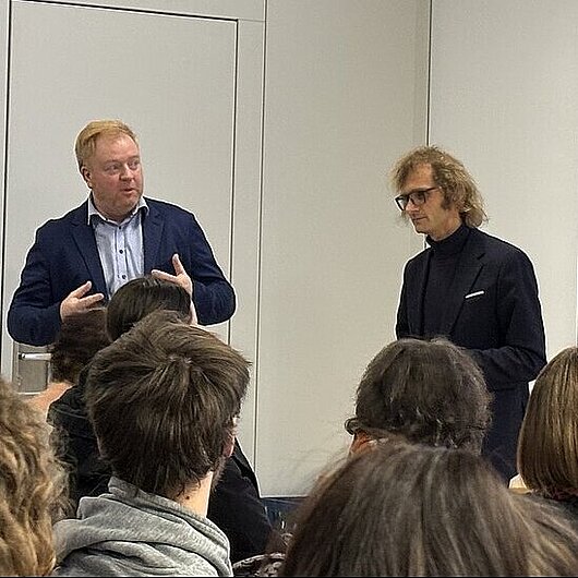 Auf dem Bild ist Herr Johannes Burgard und Herr Andreas Müßig vor einem Publikum zu sehen.