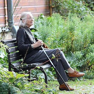 Eine alte Dame sitzt auf einer Bank