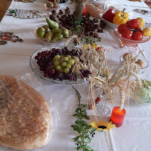 Ein Erntedank-Buffet mit Brot, Ähren, Obst und Gemüse.