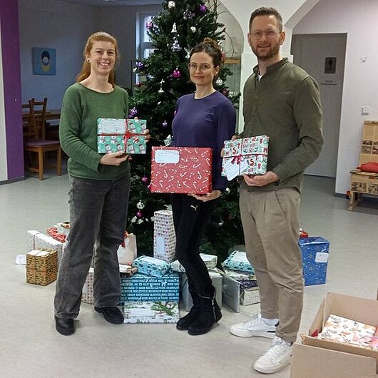 Übergabe der Geschenke vor dem Weihnachtsbaum