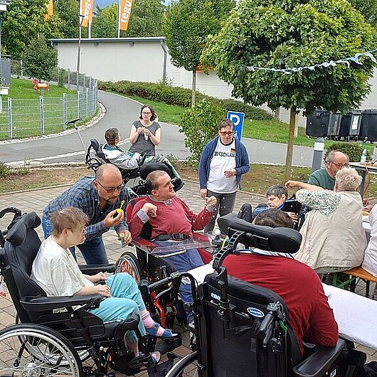 Viele Menschen sitzen am Tisch, ein Mann bläst Seifenblasen