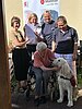Eine alte Dame im Rollstuhl begrüßt einen Malteser Therapiehund