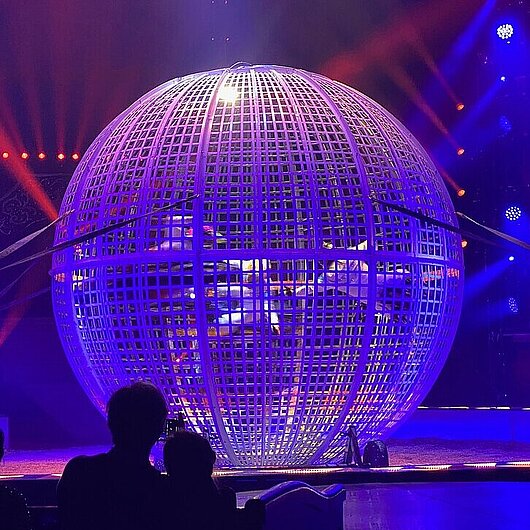 Artisten auf Mortorrädern in einer großen Kugel