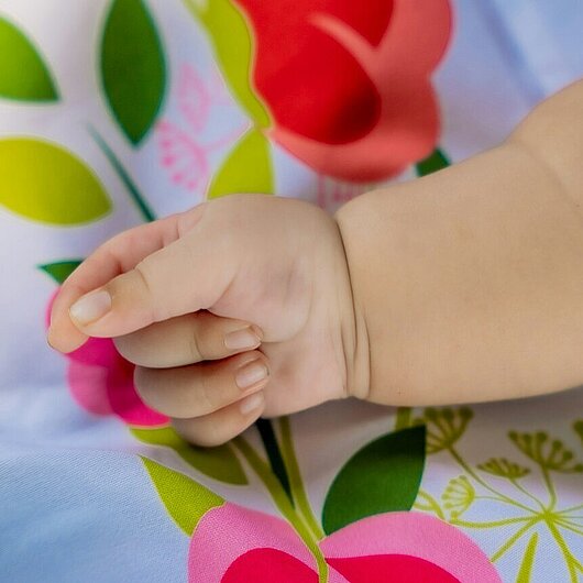 Die Hand eines Babyas auf einem geblümten Kissen (Foto: prabin basnet // unsplash)