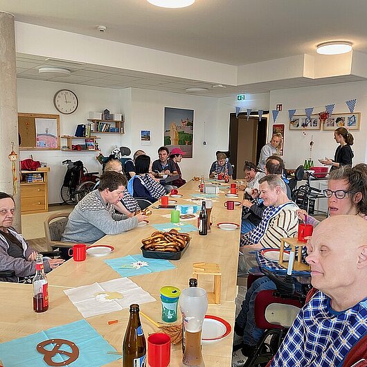 Die Bewohner sitzen an einer langen Tafel mit vielen Leckereien