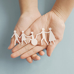 Auf Handflächen liegende ausgeschnittene Papierfiguren als Behinderte und Nichtbehinderte (Foto: SewcreamStudio/stock.adobe.com)