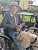 Ein Malteser Therapiehund legt seinen Kopf auf das Bein einer alten Dame im Rollstuhl