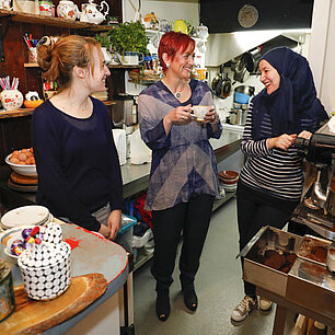 Drei mitarbeitende Frauen unterhalten sich in der Küche eines Cafés