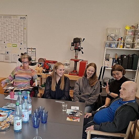 Man sieht viele Personen, die um einen Tisch sitzen