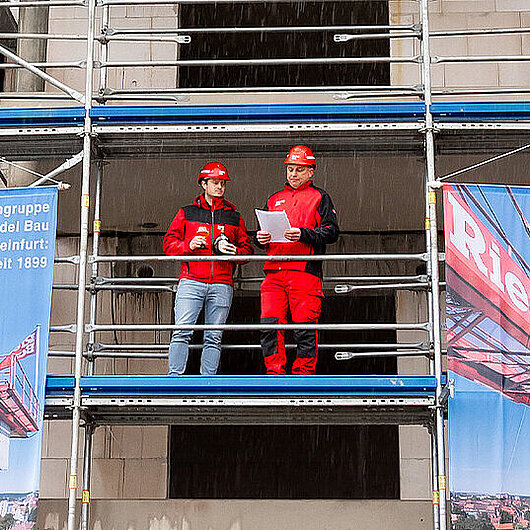Zwei Männer mit Helm auf eine Baugerüst