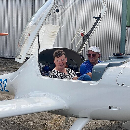 Man sieht zwei Menschen lachend im Flugzeug sitzen